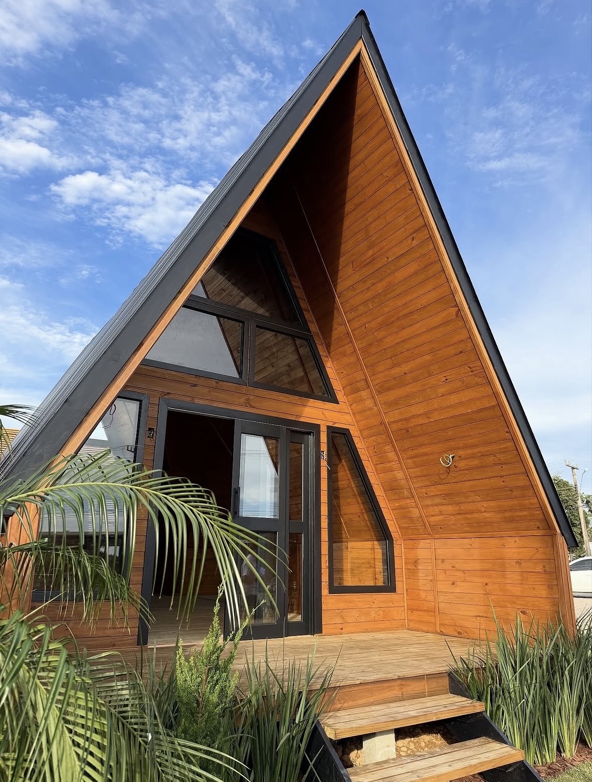 Chalé A-frame com fachada em madeira e céu azul