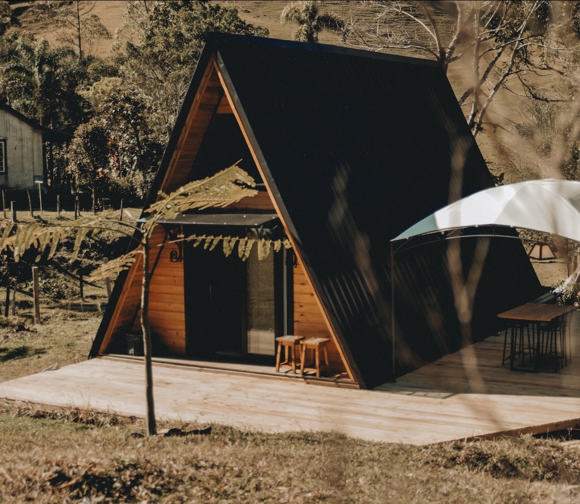 Chalé A-frame compacto com deck de madeira ao pôr do sol